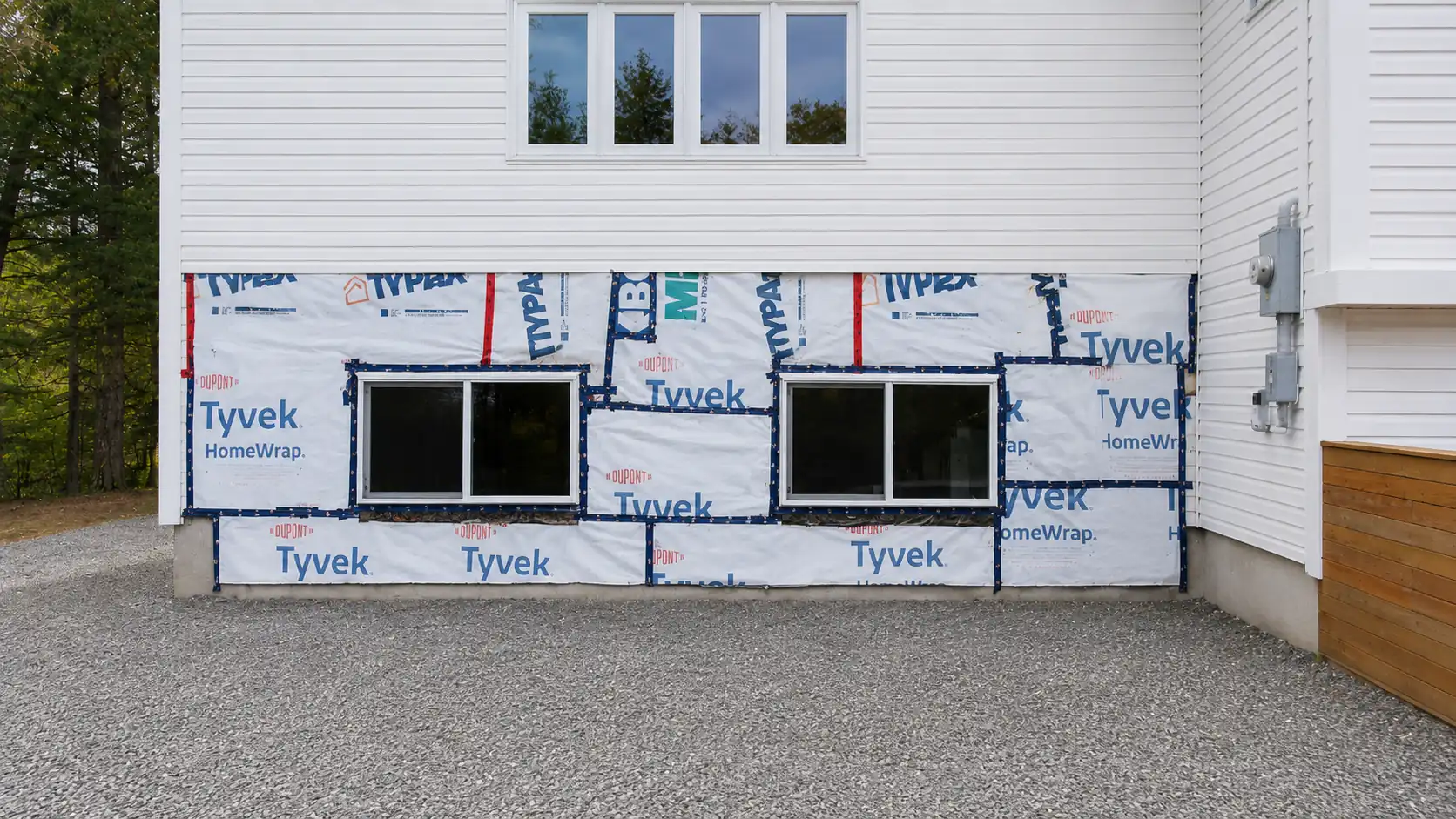Window replacement in Comox Valley — lower windows installed with Tyvek wrap before siding and garage doors